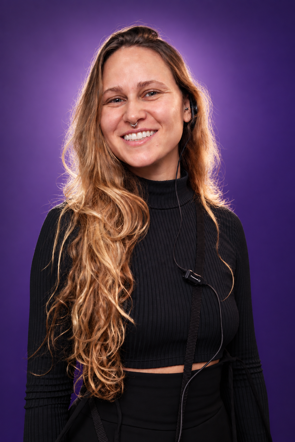 Elisa Helman sorrindo, com headset de produção e fundo roxo